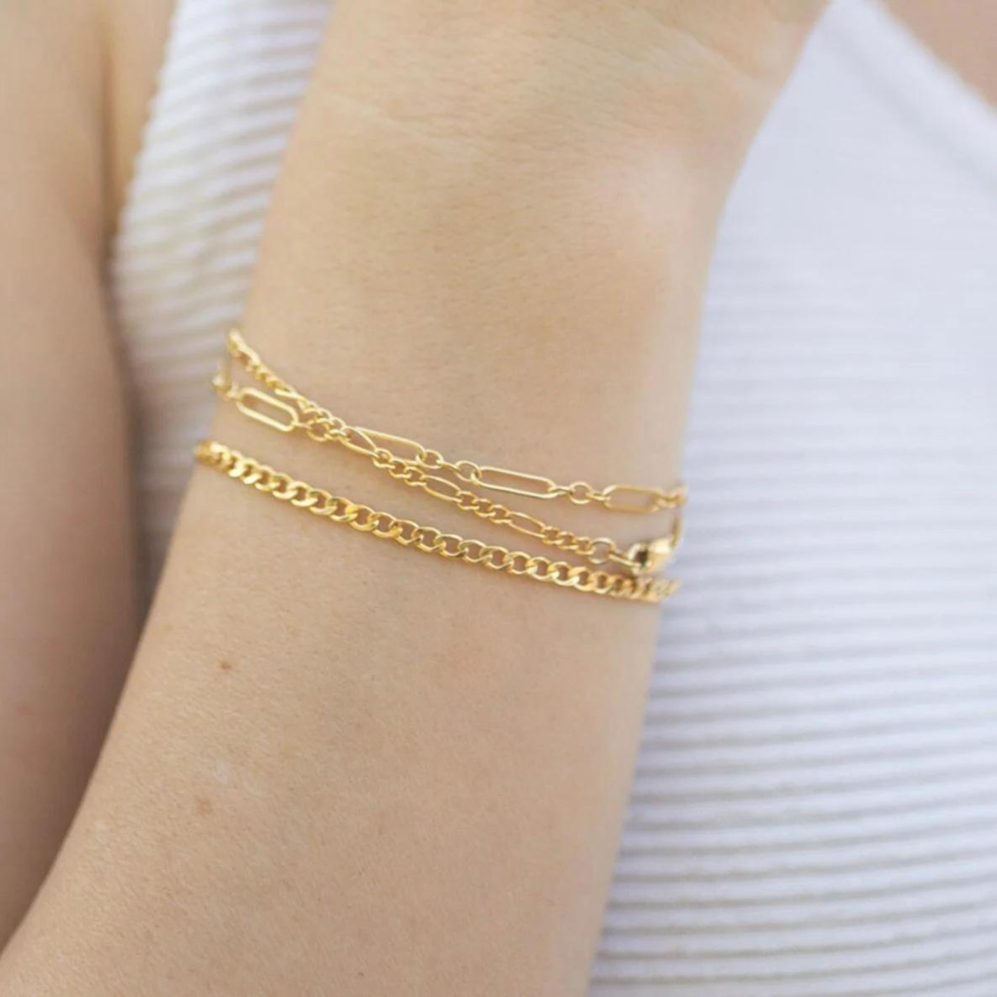 Gold bracelets on a wrist with a white background