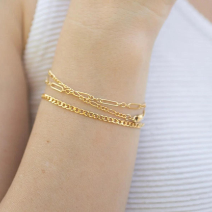 Gold bracelets on a wrist with a white background